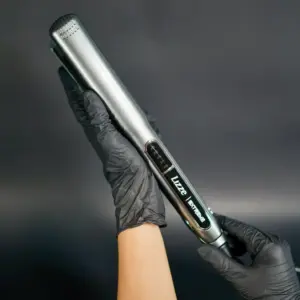 Plancha de pelo profesional Lizze Extreme gris metálico con placas de titanio y control digital, sostenida por manos con guantes negros sobre fondo oscuro